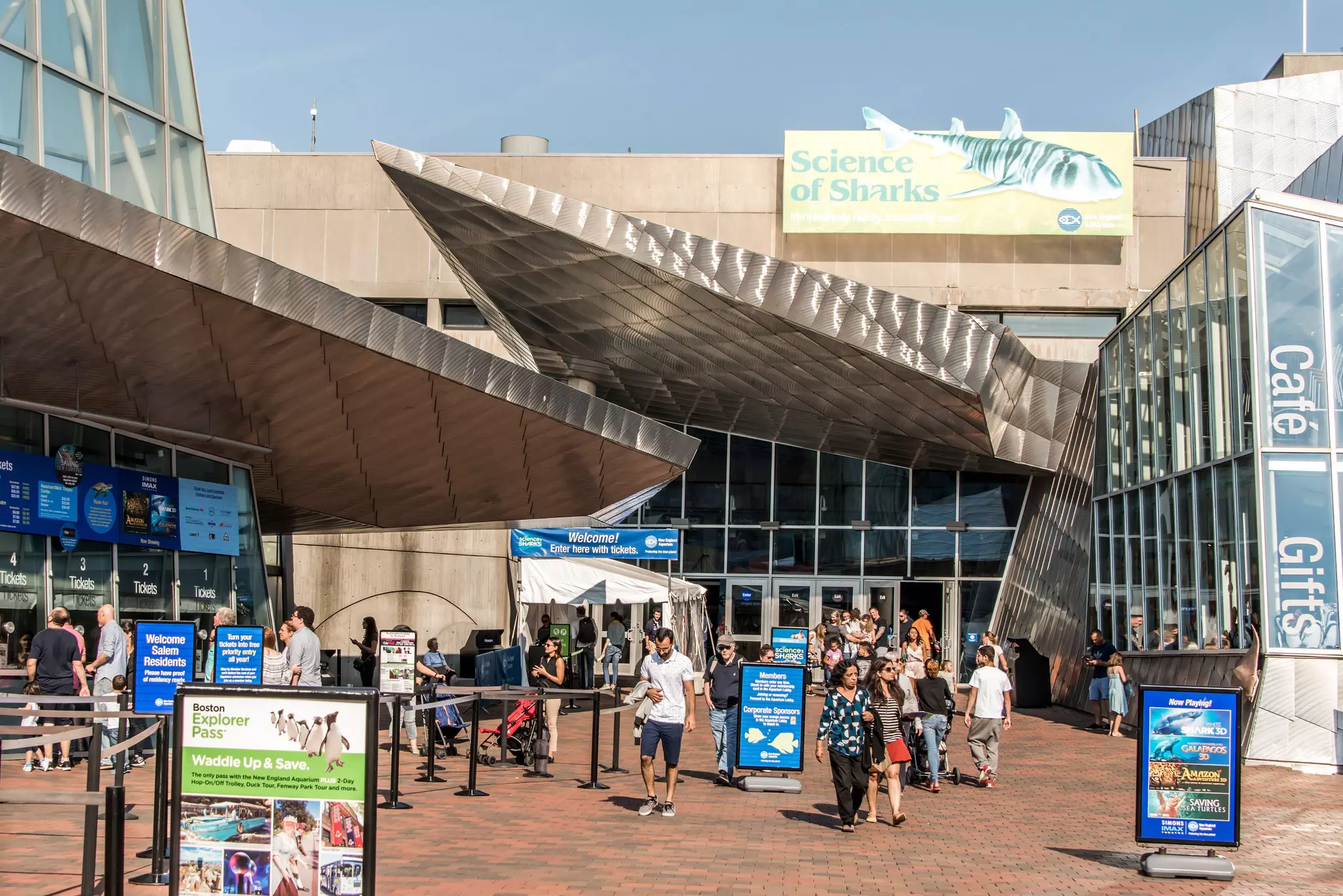 People exiting and entering a building with signs outside advertising ticketing and shows