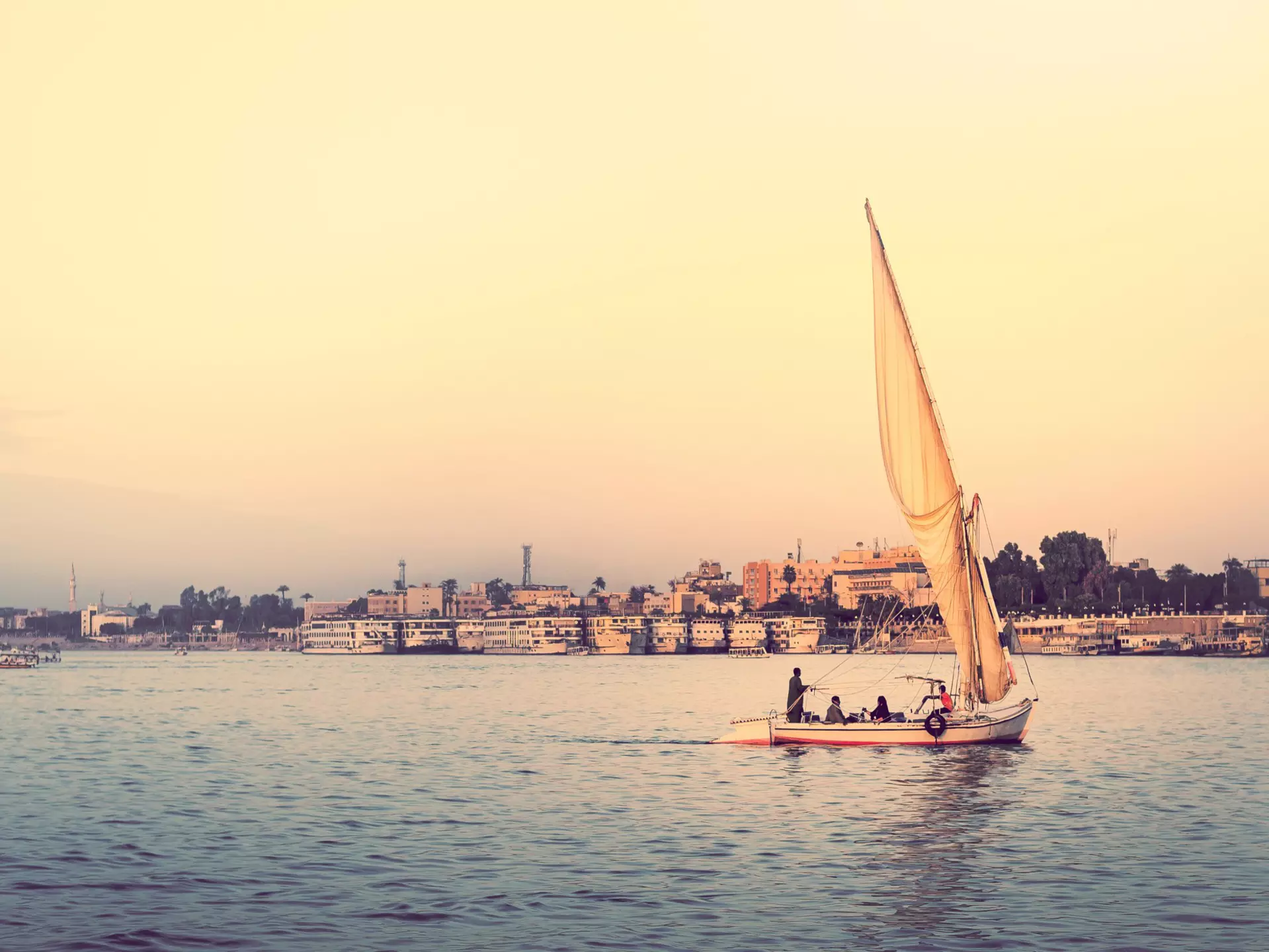 A small sailboat on a wide river at sunset.