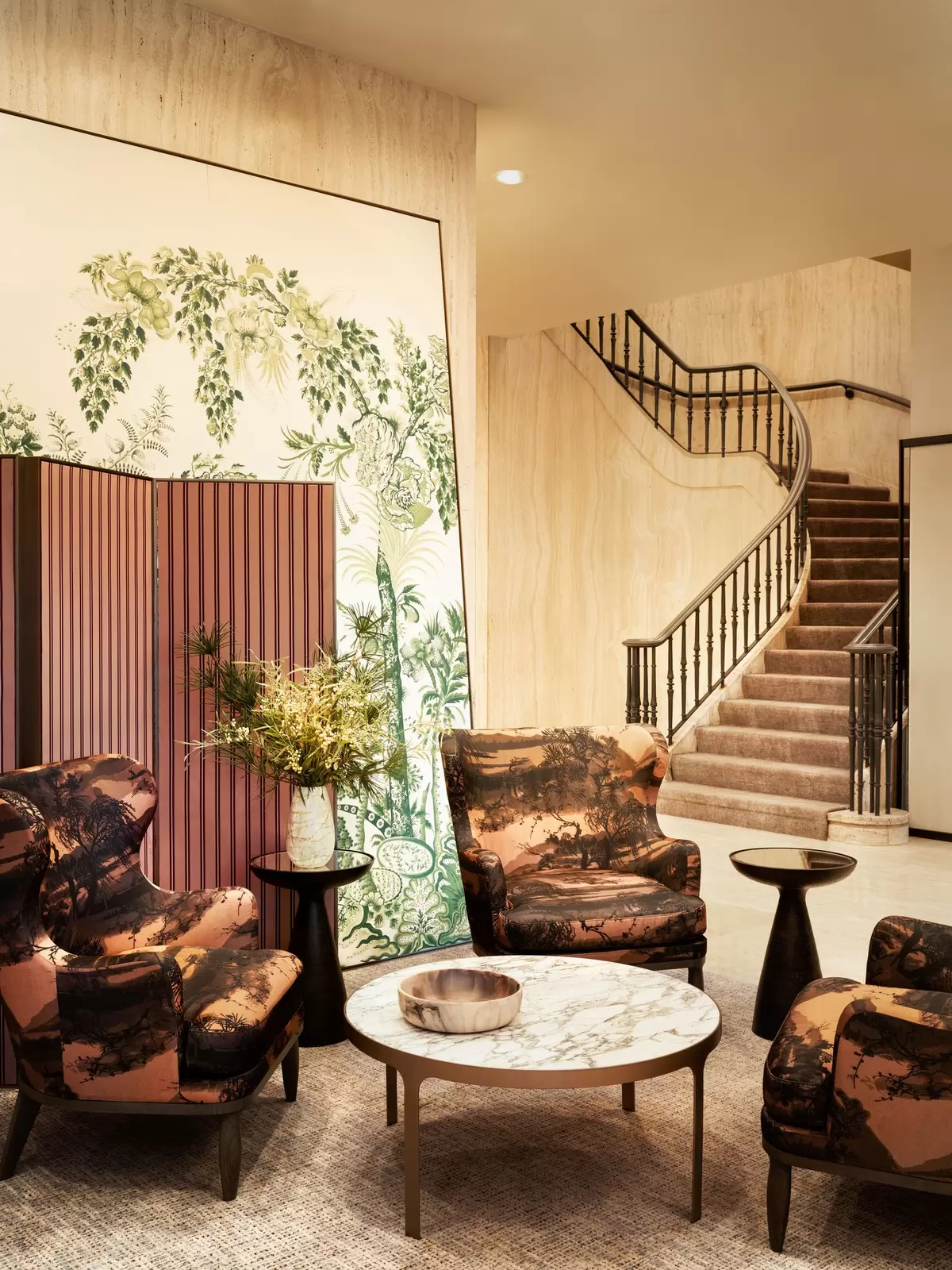 Armchairs are arranged around a low table; a staircase leads up to one side.