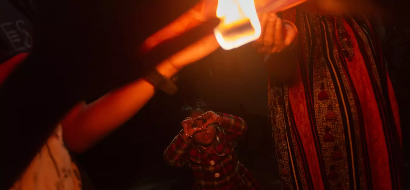 A young child watches as a lantern is lit