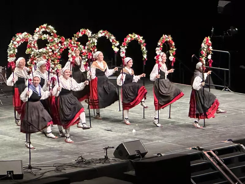 Women dancers in black and white dresses with red and white flowers over their heads