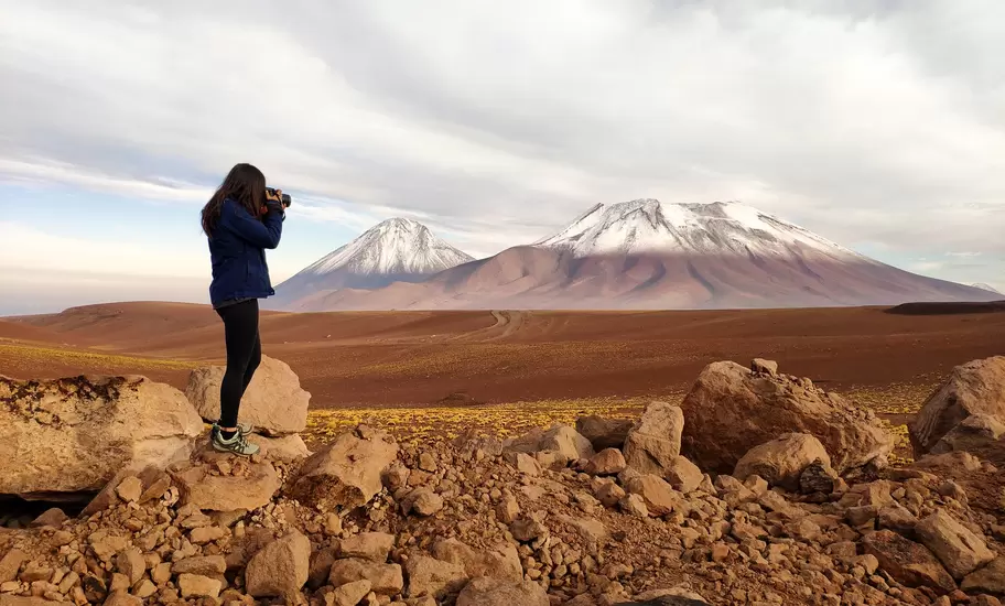 Silhouette of a tourist woman photographing Licancabur and Juriques volcanoes in the border between Chile and Bolivia