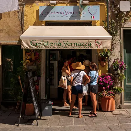 People in summer clothes queue outside an ice-cream shop in Vernazza.