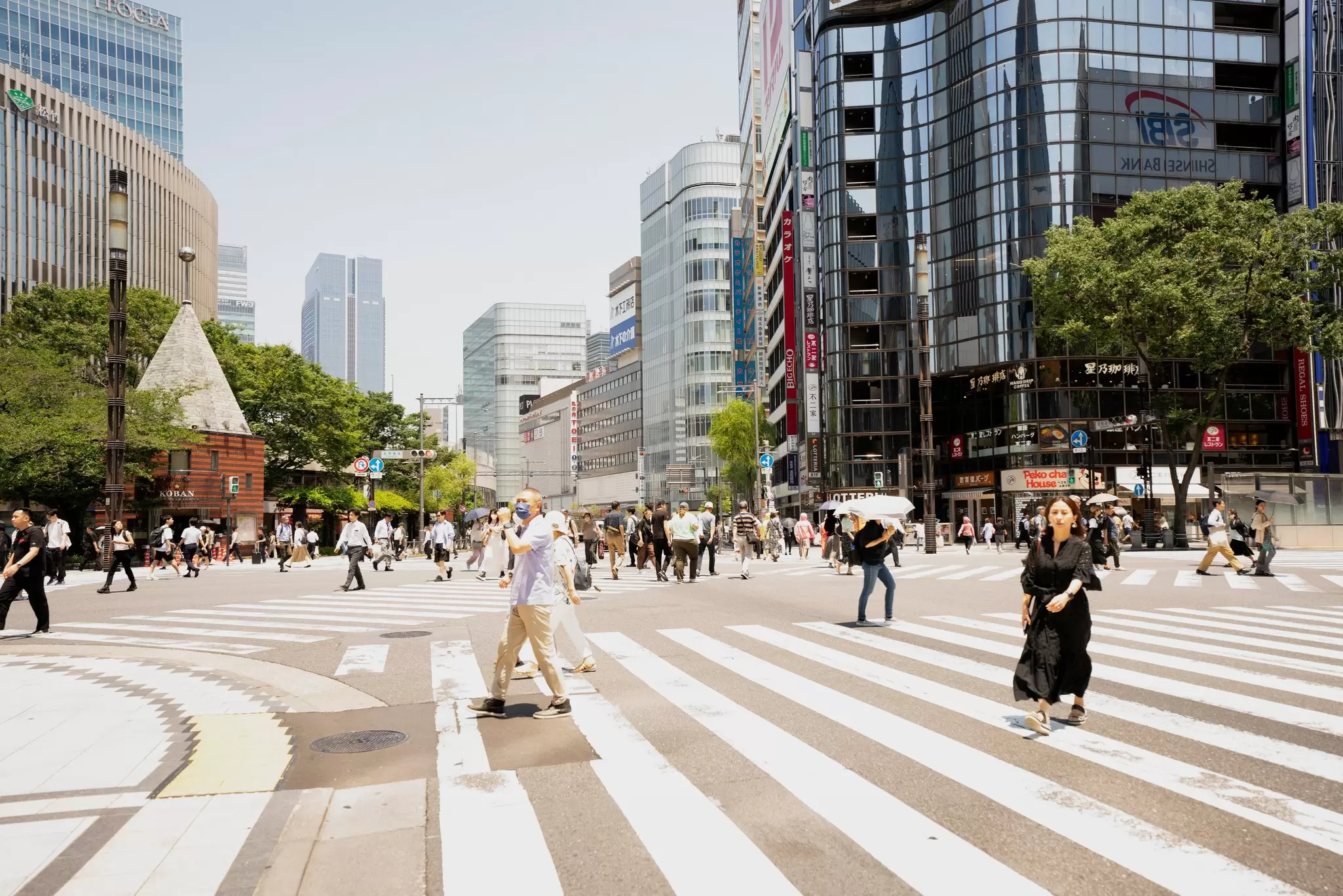 People crossing large crosswalks amid large, tall glass buildings in Tokyo's Roppongi neighborhood