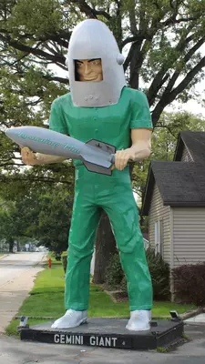 A huge fiberglass astronaut stands at the side of a road.