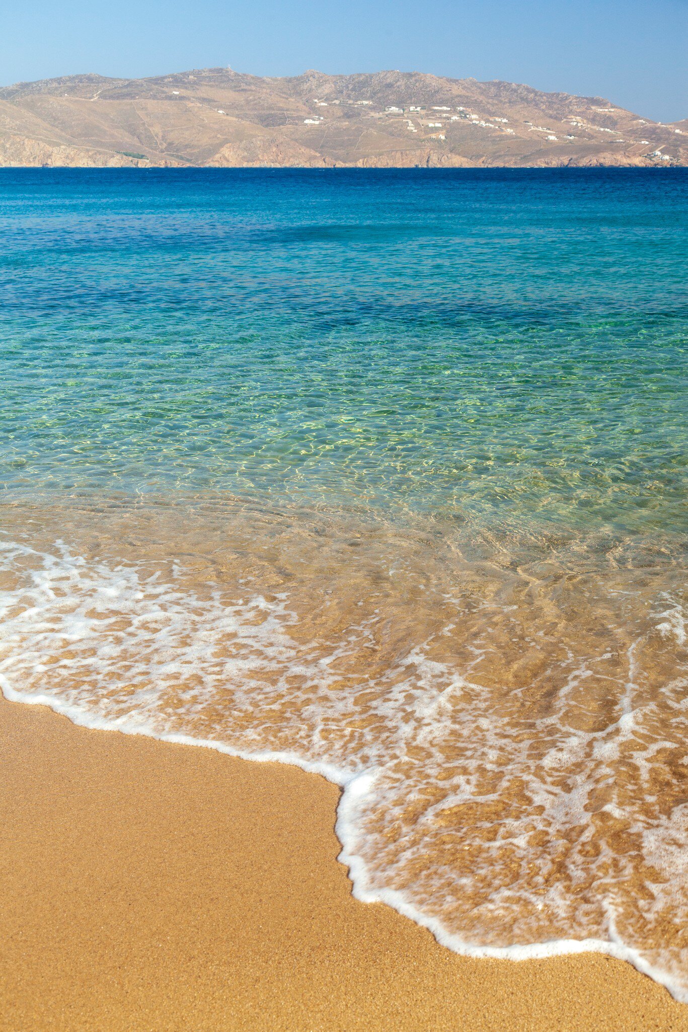 View of waves washing onto Agios Sostis Beach on the island of Mykonos in Greece.