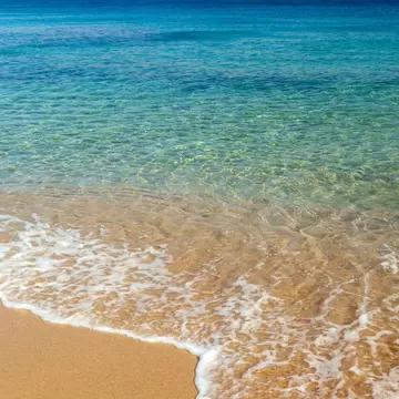 View of waves washing onto Agios Sostis Beach on the island of Mykonos in Greece.