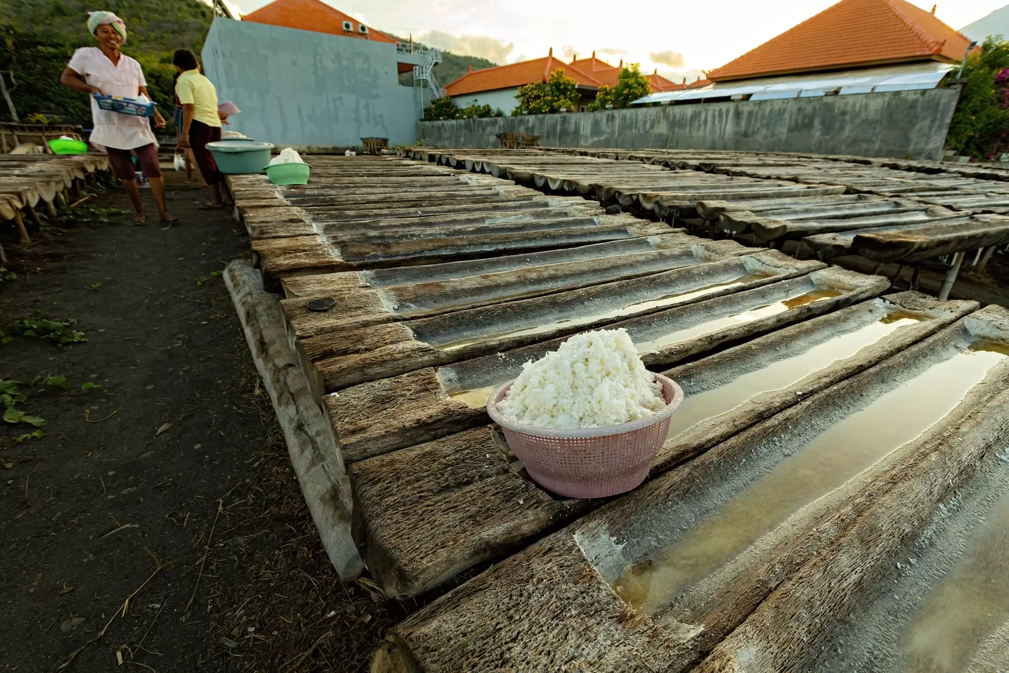 AMED, BALI - November 2022: Woman next to the wooden trays for the sea salt production in Amed, Bali, License Type: media, Download Time: 2025-03-01T19:36:01.000Z, User: Ppeterson948, Editorial: true, purchase_order: 56530 - Guidebooks, job: Global Publishing WIP, client: Global Publishing WIP, other: Pia Peterson Haggarty