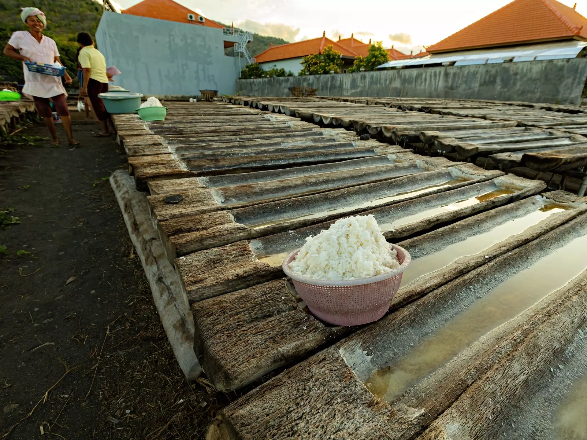 AMED, BALI - November 2022: Woman next to the wooden trays for the sea salt production in Amed, Bali, License Type: media, Download Time: 2025-03-01T19:36:01.000Z, User: Ppeterson948, Editorial: true, purchase_order: 56530 - Guidebooks, job: Global Publishing WIP, client: Global Publishing WIP, other: Pia Peterson Haggarty