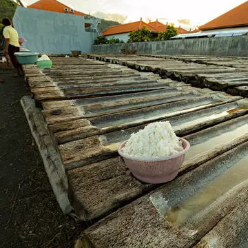 AMED, BALI - November 2022: Woman next to the wooden trays for the sea salt production in Amed, Bali, License Type: media, Download Time: 2025-03-01T19:36:01.000Z, User: Ppeterson948, Editorial: true, purchase_order: 56530 - Guidebooks, job: Global Publishing WIP, client: Global Publishing WIP, other: Pia Peterson Haggarty