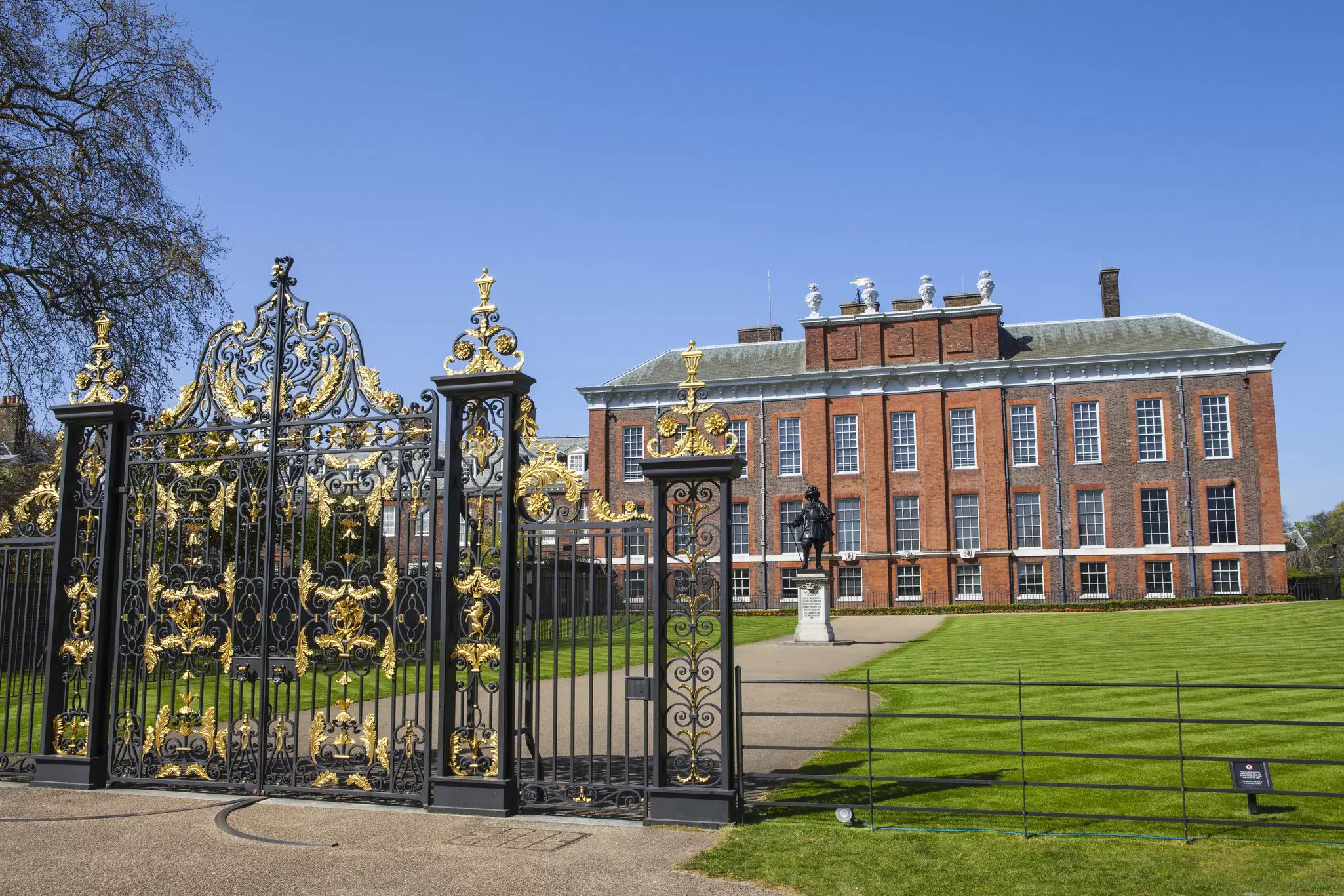 Exterior of Kensington Palace with the statue of King William III in the foreground on a sunny day in London, UK.