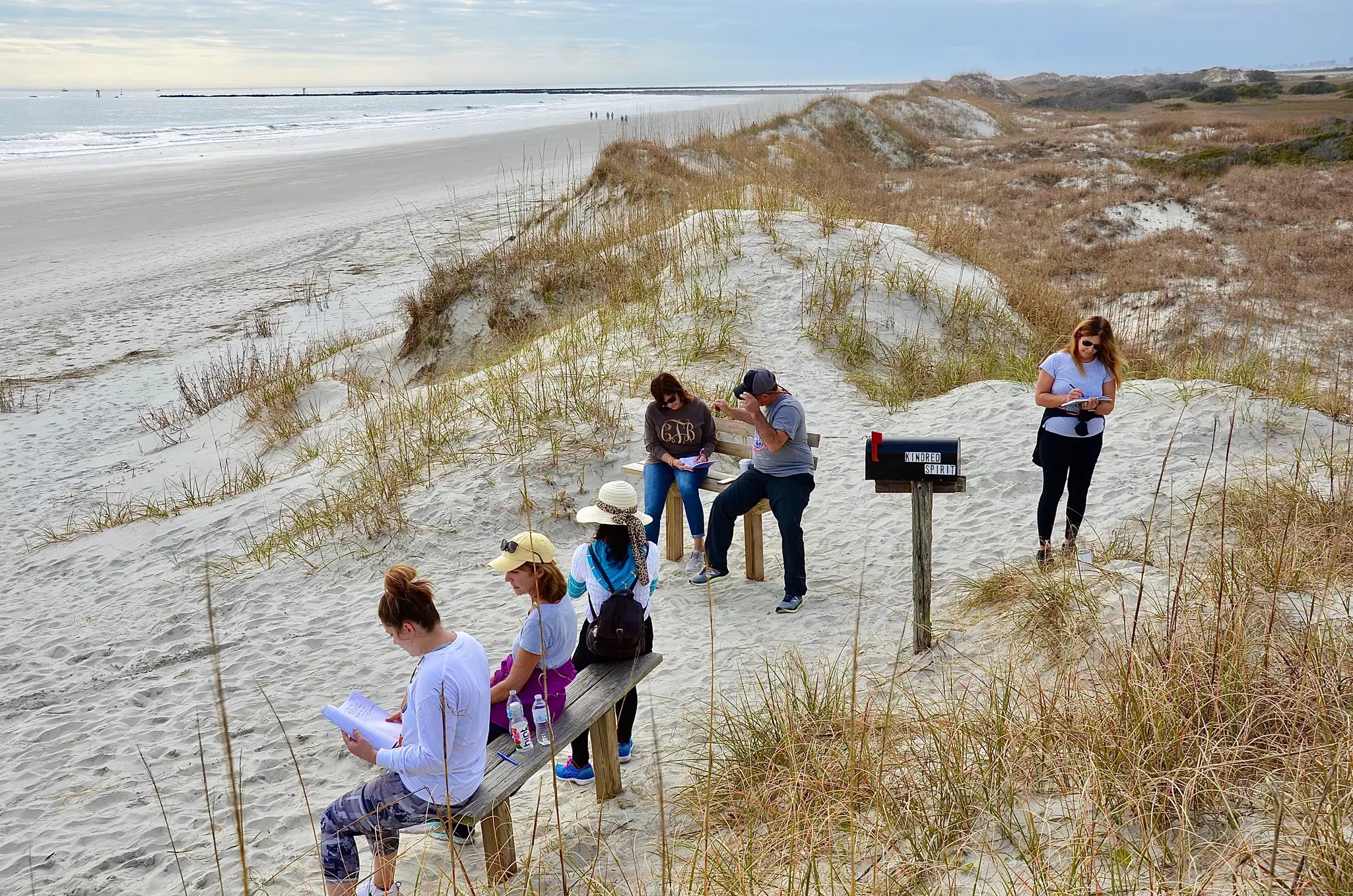 Group of people gathering around Kindred Spirit Mailbox, an unique landmark on the Sunset Beach, to write down their stories or secrets as spiritual release.