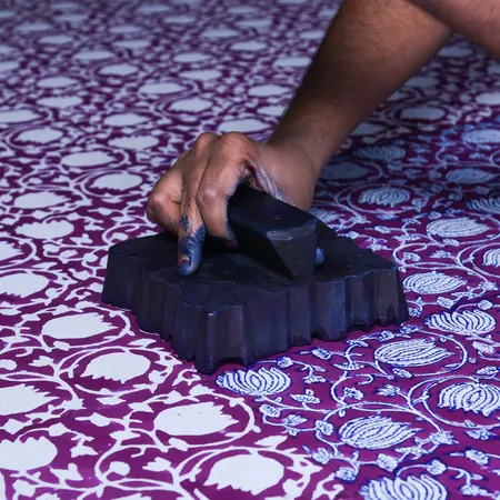 Closeup of hand block printing on purple fabric.