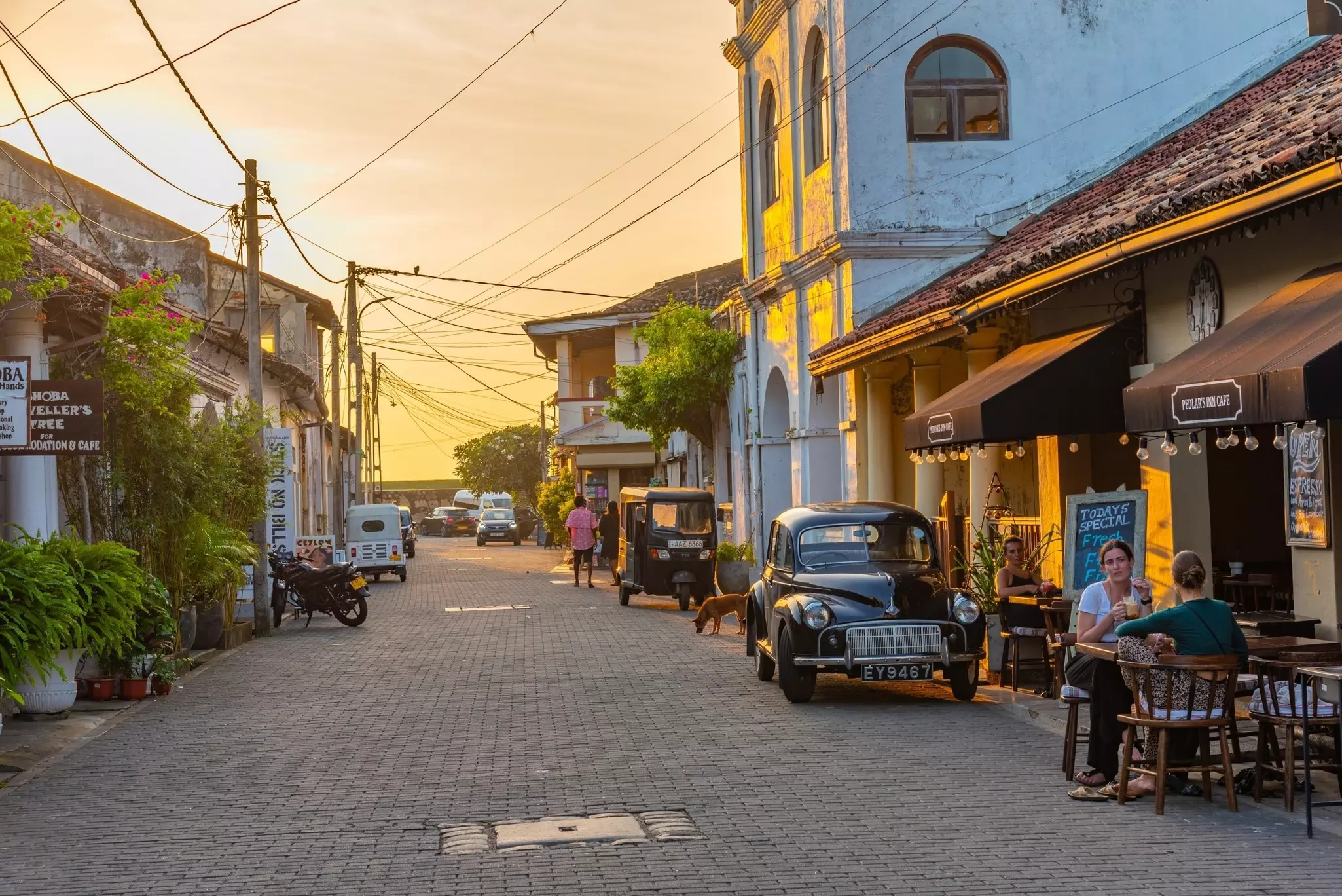 People sit at tables outside a cafe during sundown in Sri Lanka.