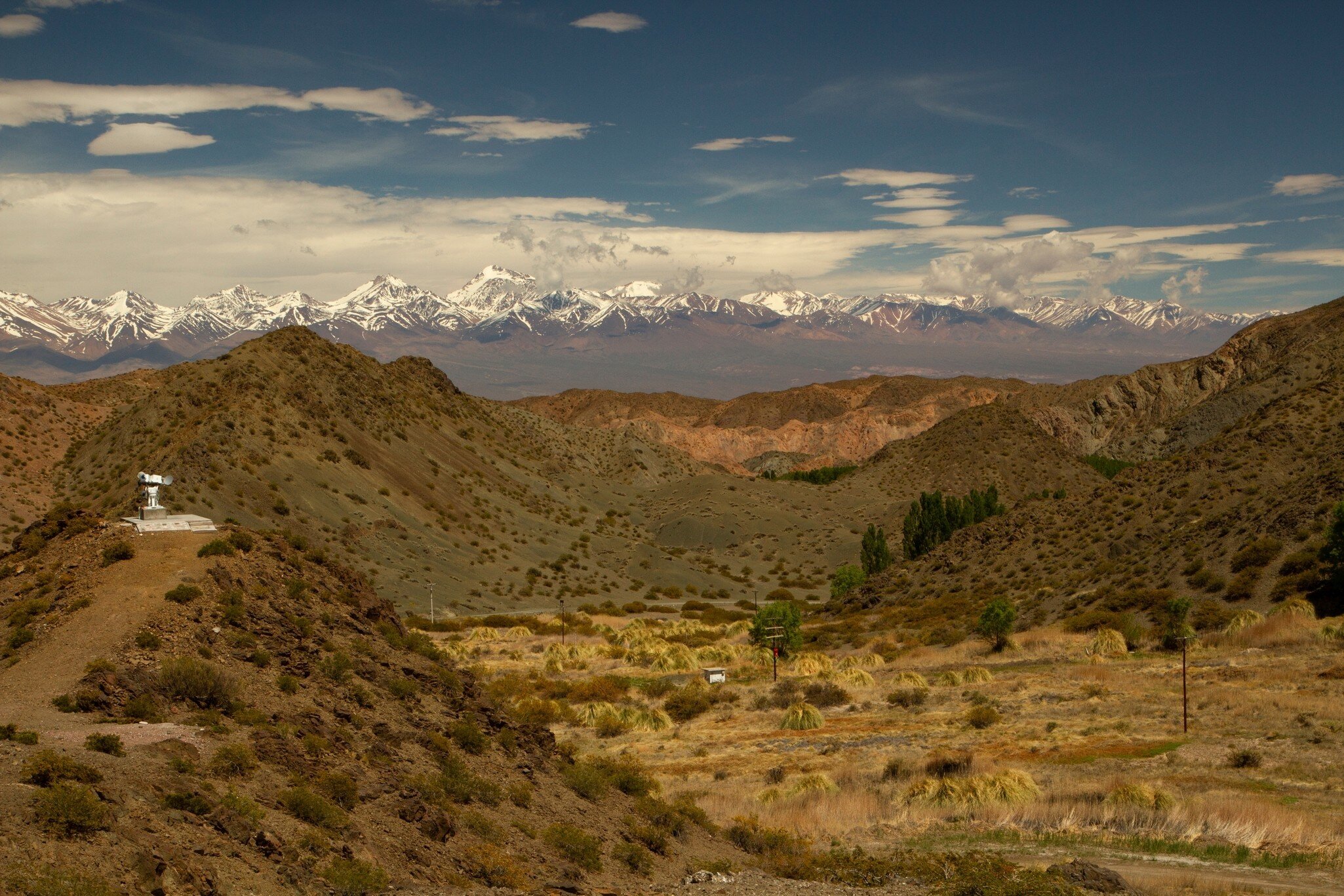 Alpine landscape. View of the arid valley and Andes cordillera mountains in the horizon, under a blue sky in Pampa del Leoncito, San Juan, Argentina.