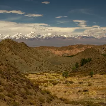 Alpine landscape. View of the arid valley and Andes cordillera mountains in the horizon, under a blue sky in Pampa del Leoncito, San Juan, Argentina.