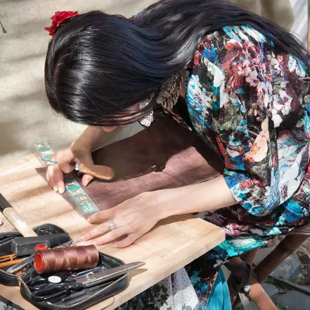 A woman artisan works on leather in a street market