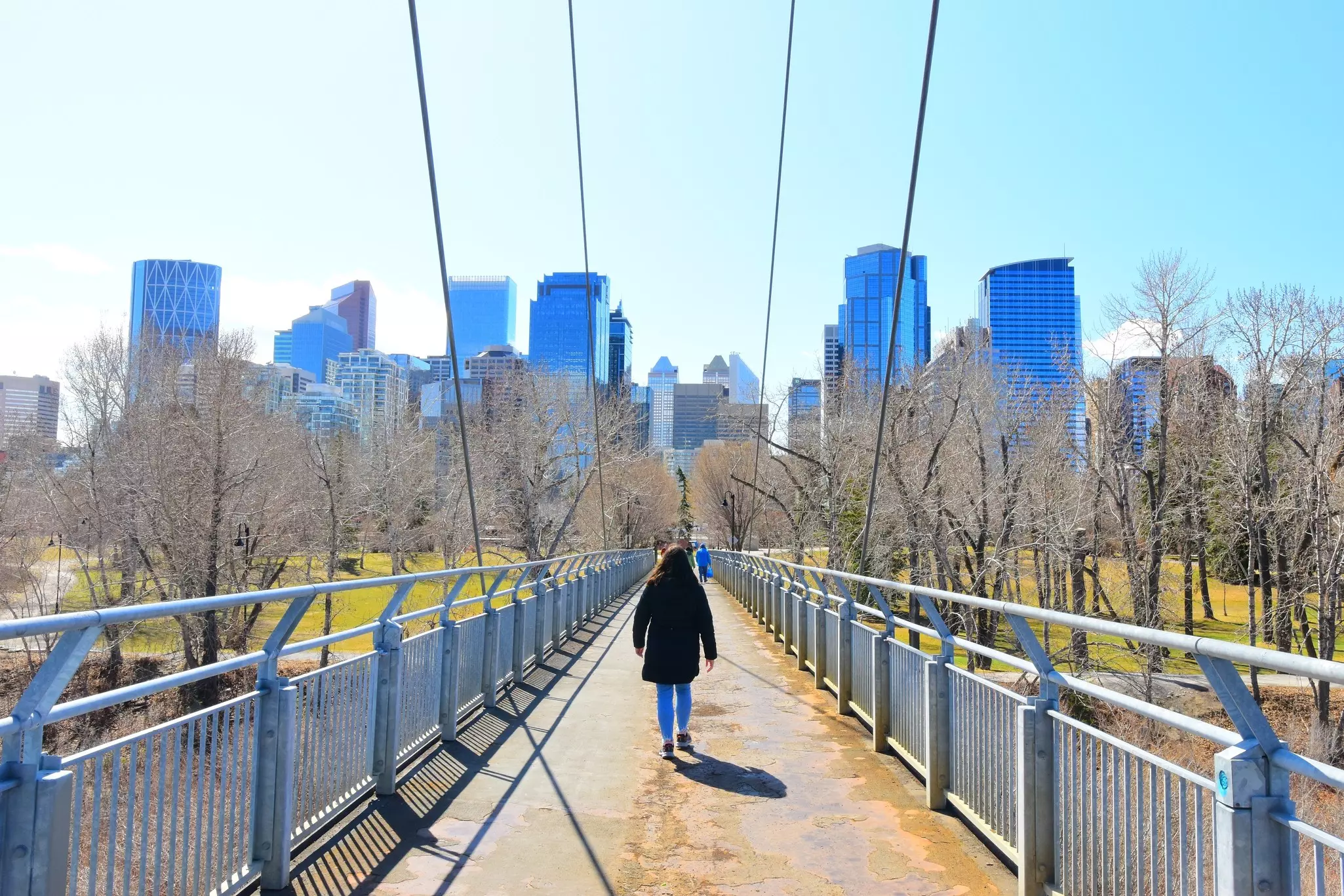 People walking on Bow River Pathway between Sunnyside and Prince's Island, with Calgary skyline in the background
