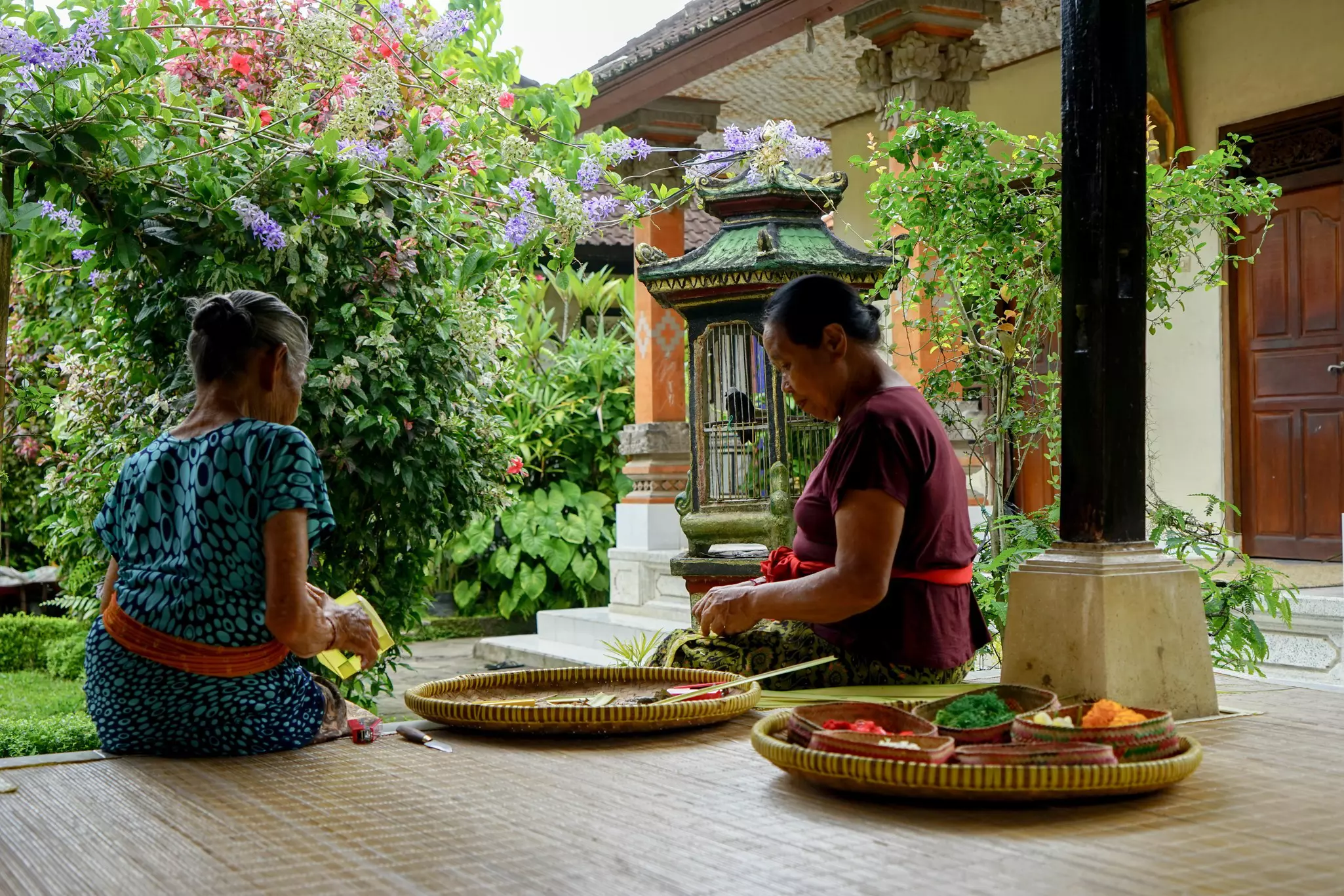 Can you keep a secret tour - women making canang sari in Bali sitting outside on a deck
