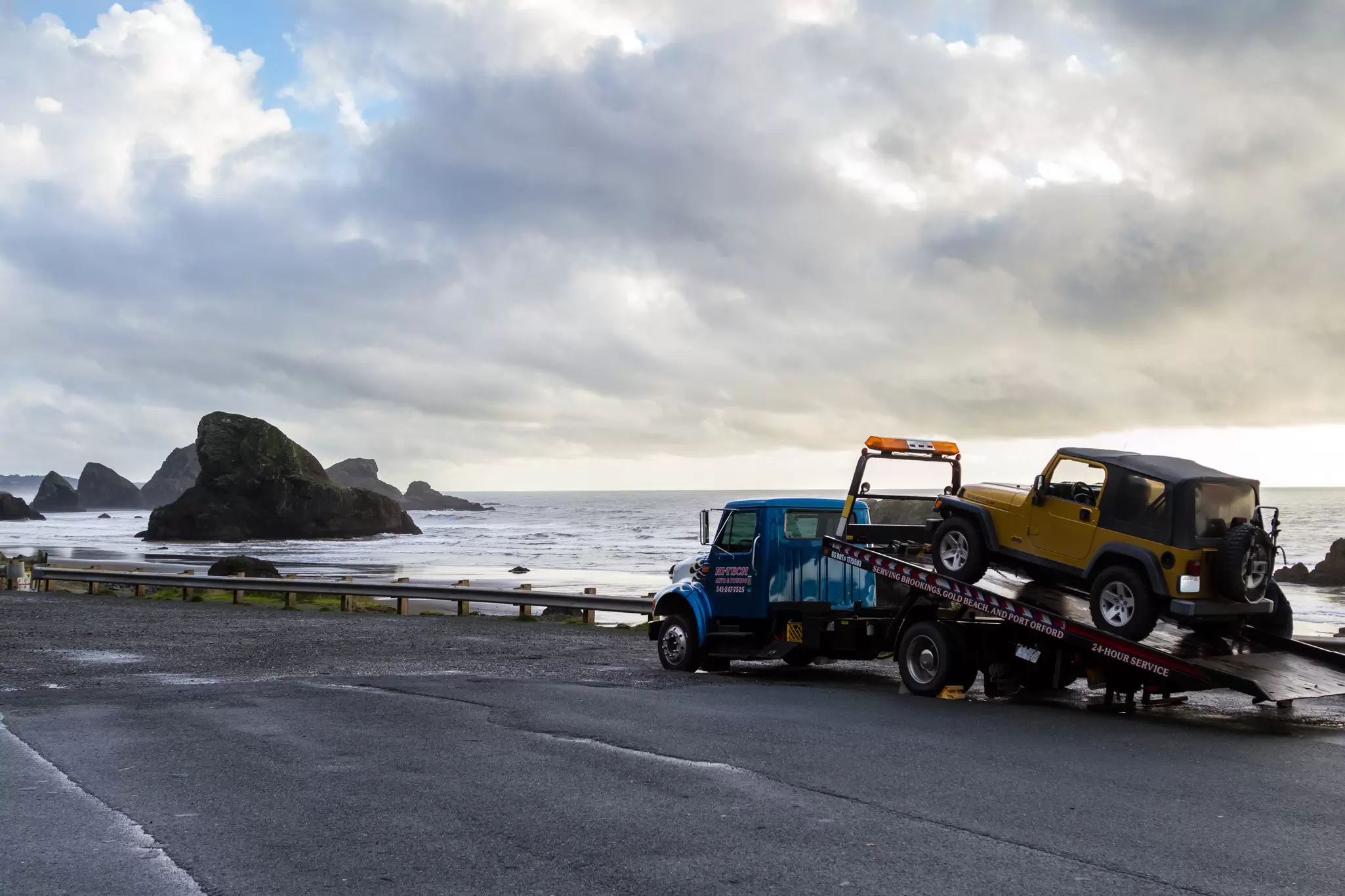 Meyers Beach, Oregon - October 27: Flat bed tow truck loading a broken vehicle with a beautiful coastal landscape in the background. October 27 2016, Meyers Beach, Oregon., License Type: media, Download Time: 2025-11-11T18:32:27.000Z, User: meg3348277, Editorial: true, purchase_order: 56530 - Guidebooks, job: Global Publishing-WIP, client: Lonely Planet 'Journey - Pacific Coast Highway 1', other: Megan Cassidy