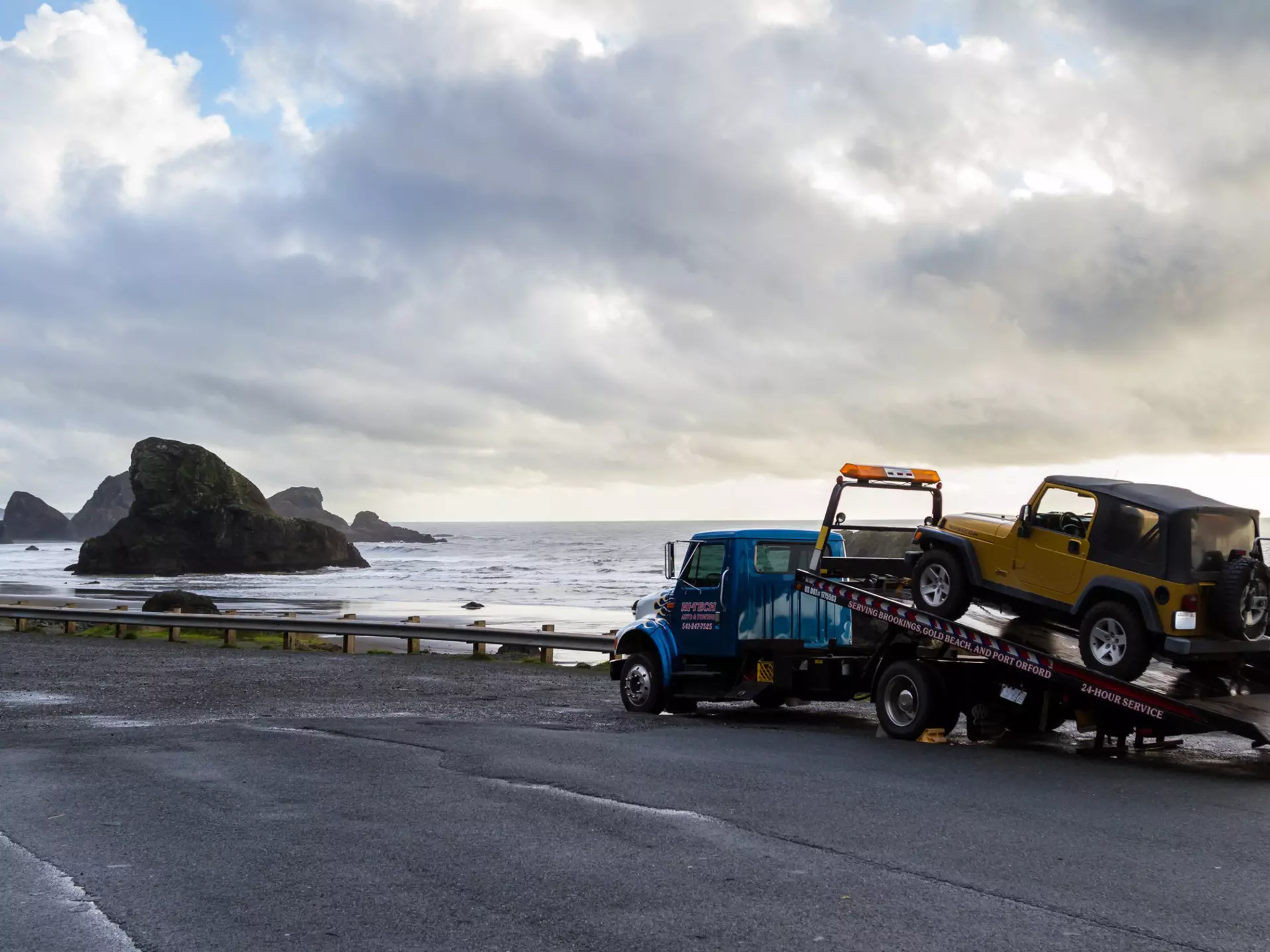 Meyers Beach, Oregon - October 27: Flat bed tow truck loading a broken vehicle with a beautiful coastal landscape in the background. October 27 2016, Meyers Beach, Oregon., License Type: media, Download Time: 2025-11-11T18:32:27.000Z, User: meg3348277, Editorial: true, purchase_order: 56530 - Guidebooks, job: Global Publishing-WIP, client: Lonely Planet 'Journey - Pacific Coast Highway 1', other: Megan Cassidy