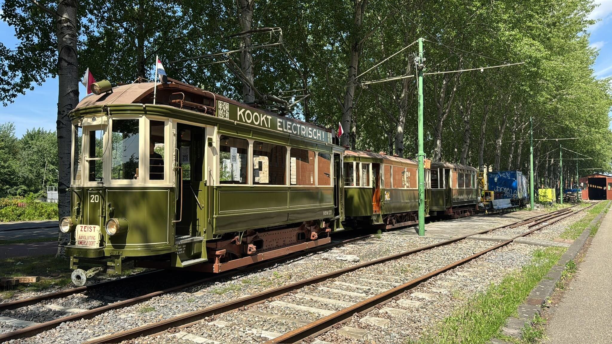 View of a historic green tram of the Electrische Museumtramlijn Amsterdam on a sunny day.