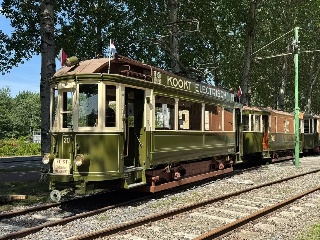 View of a historic green tram of the Electrische Museumtramlijn Amsterdam on a sunny day.