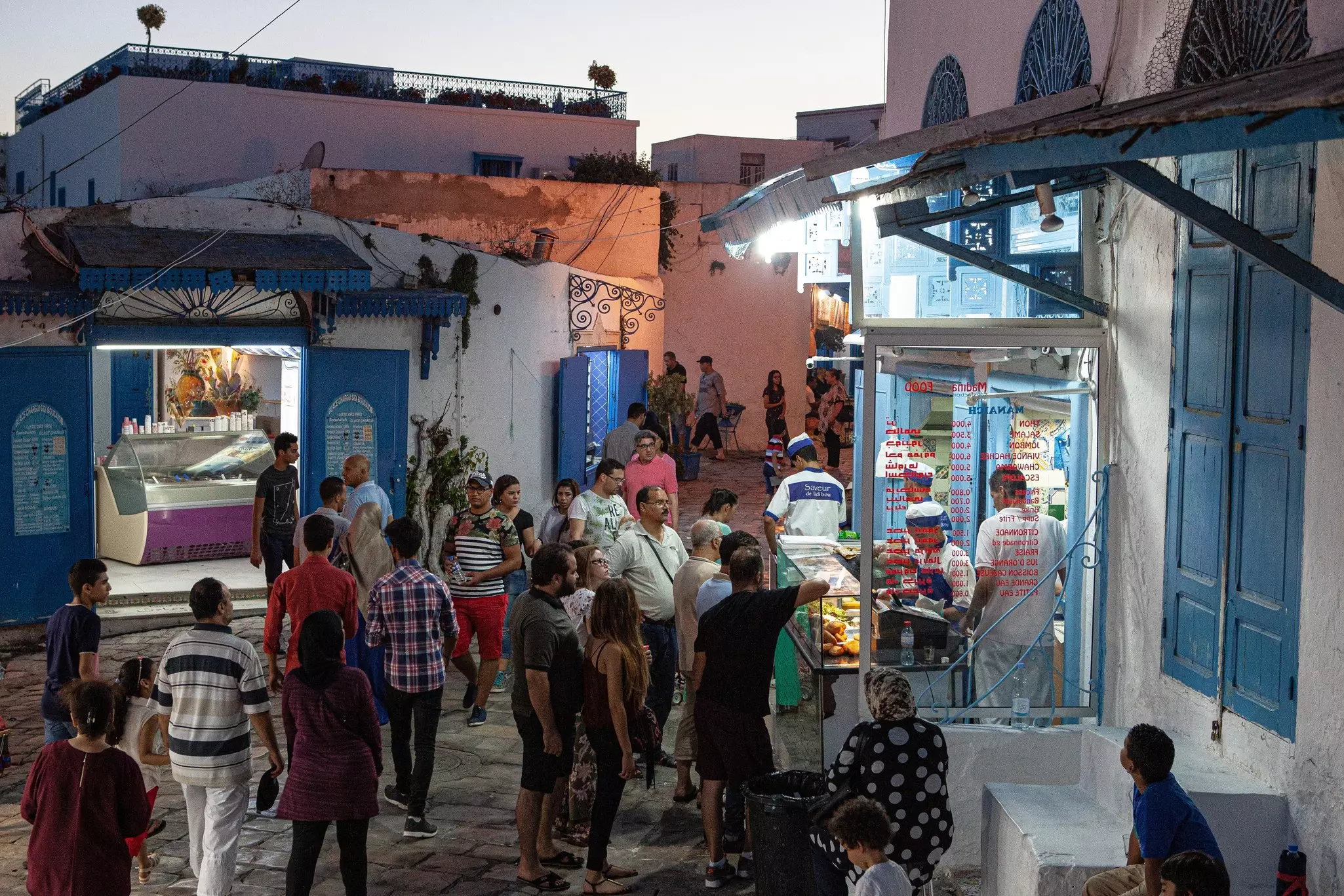 People in line outside of a restaurant at dusk.