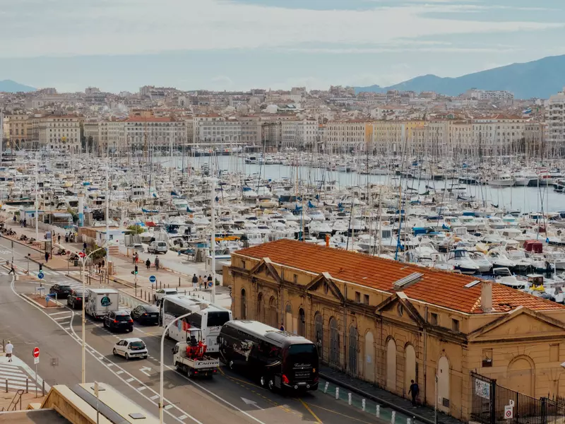 A marina filled with boats; the buildings of a city are on the far shore.