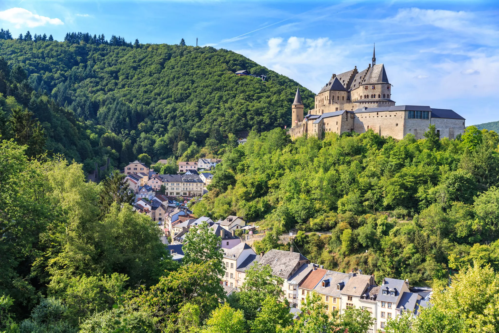 Vianden castle rises above forests and the village of Vianden in Luxembourg.