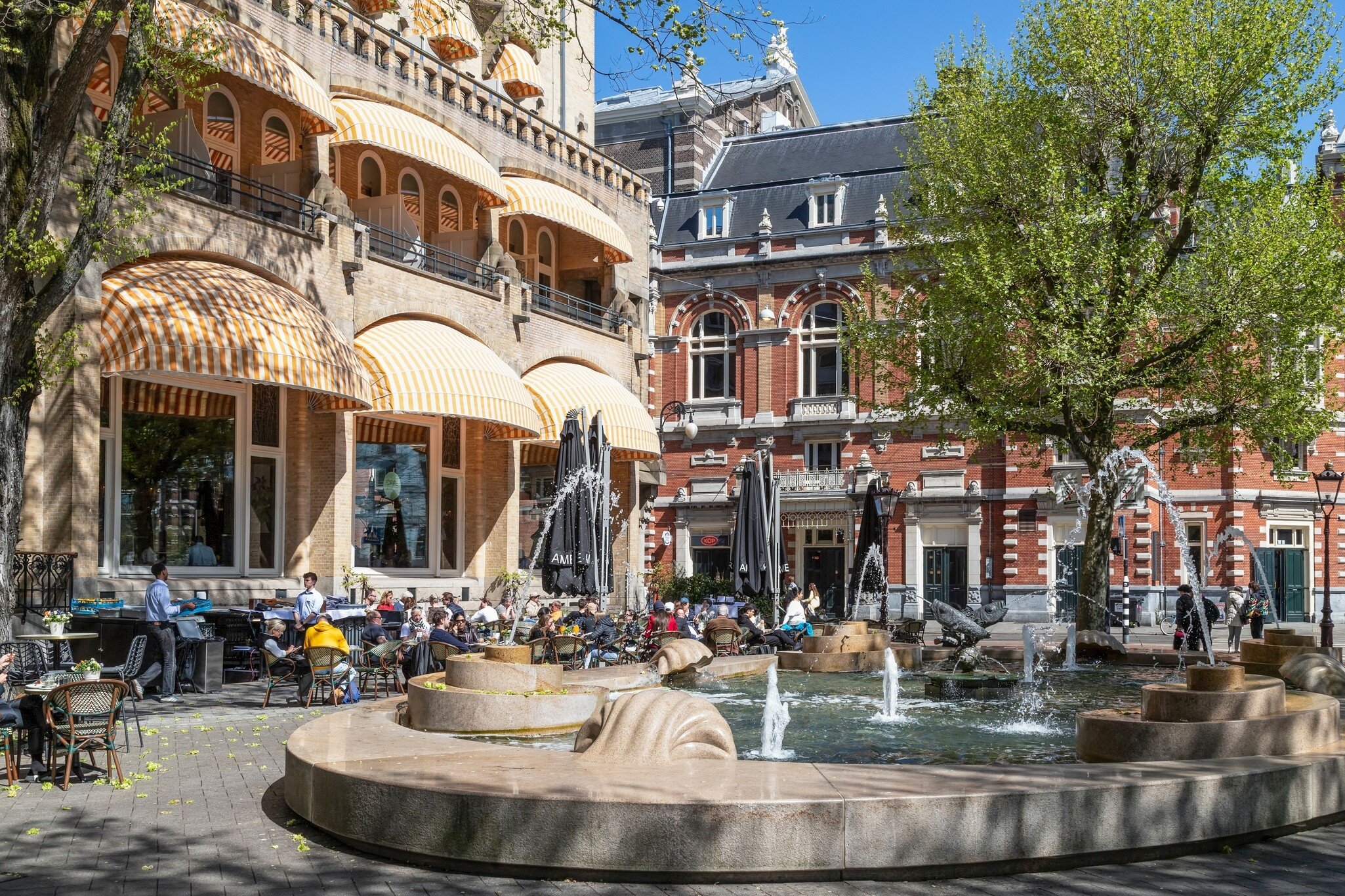 People on the terrace of the Café Americain on the Leidseplein in the center of Amsterdam on a sunny day.