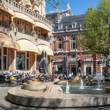 People on the terrace of the Café Americain on the Leidseplein in the center of Amsterdam on a sunny day.