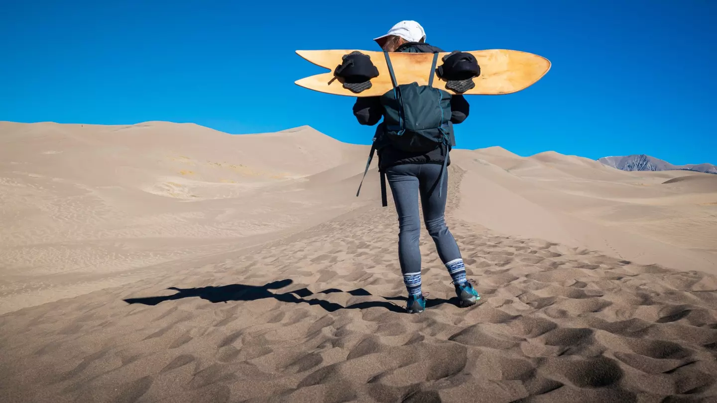 A female holds a sand board at Great Sand Dunes National Park, Colorado, USA