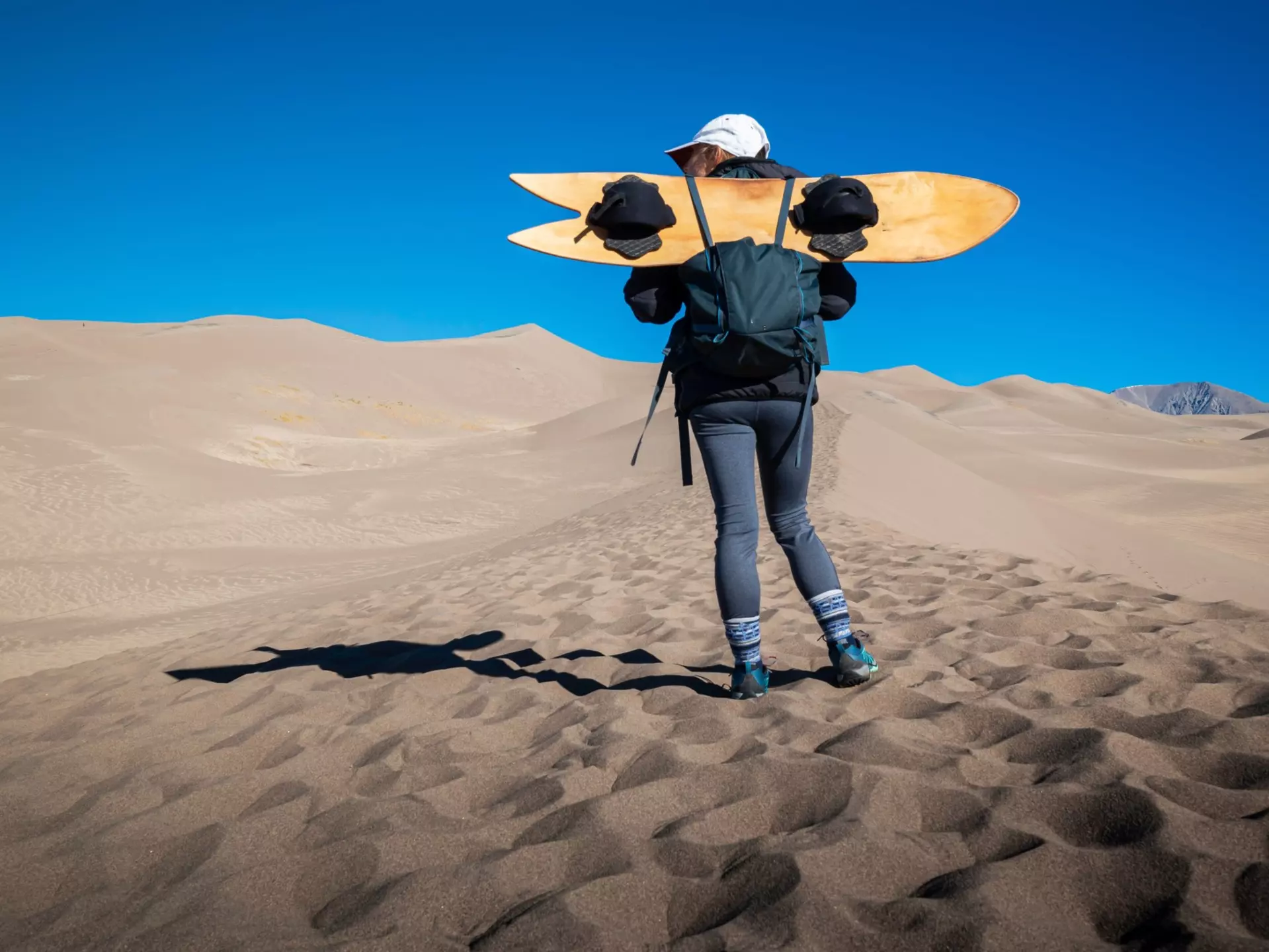 A female holds a sand board at Great Sand Dunes National Park, Colorado, USA