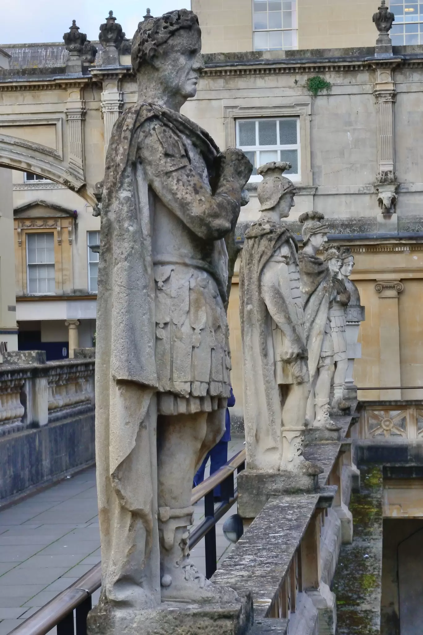 Stone statues stand in a row above a Roman open-air pool
