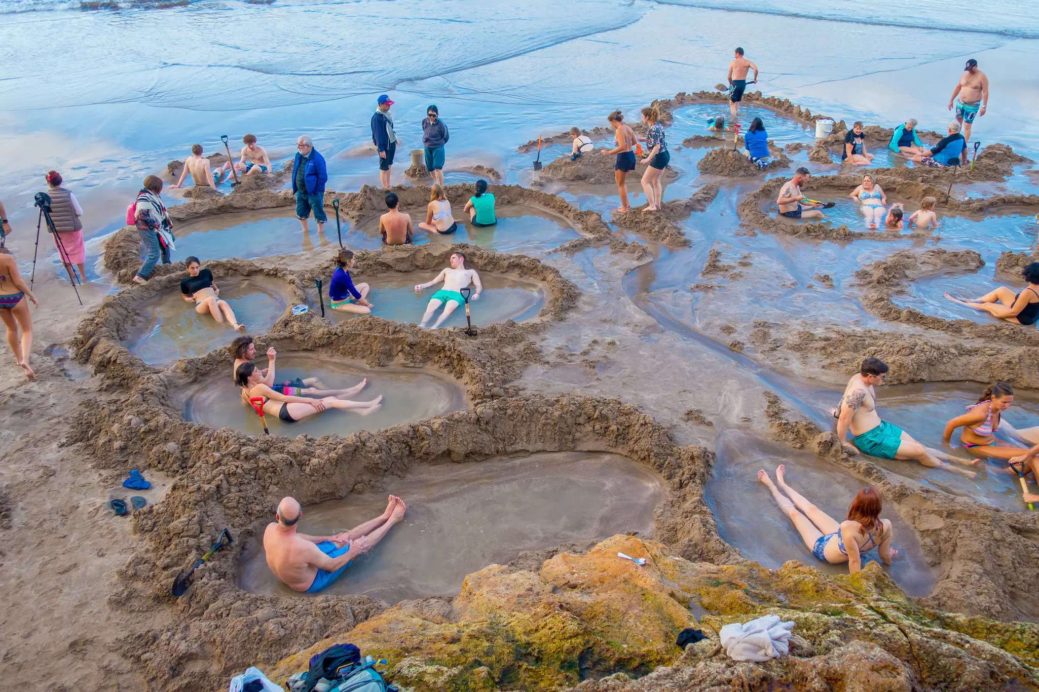 People in small pools of water by a beach.