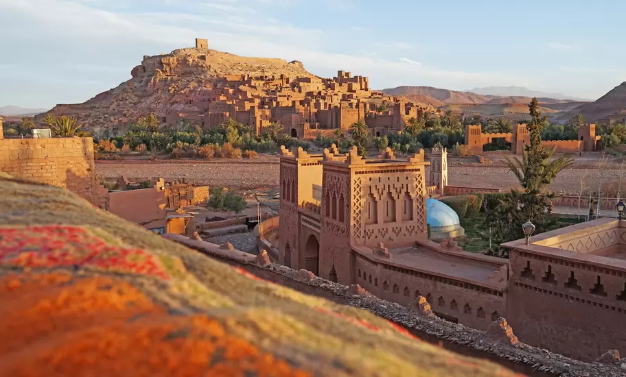 Earthen kasbahs of Aït Ben Haddou climb a hill topped by a granary in central Morocco, a decorated gatehouse in front