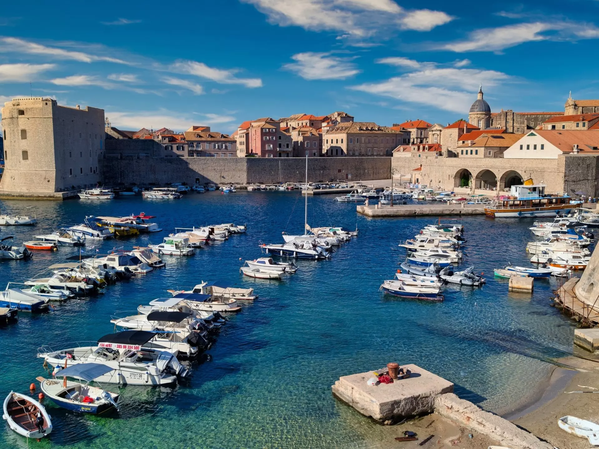 A small harbor below city walls and a fortress.
