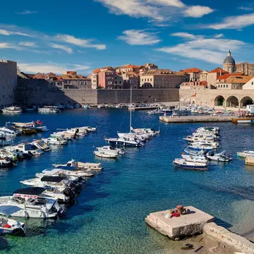 A small harbor below city walls and a fortress.