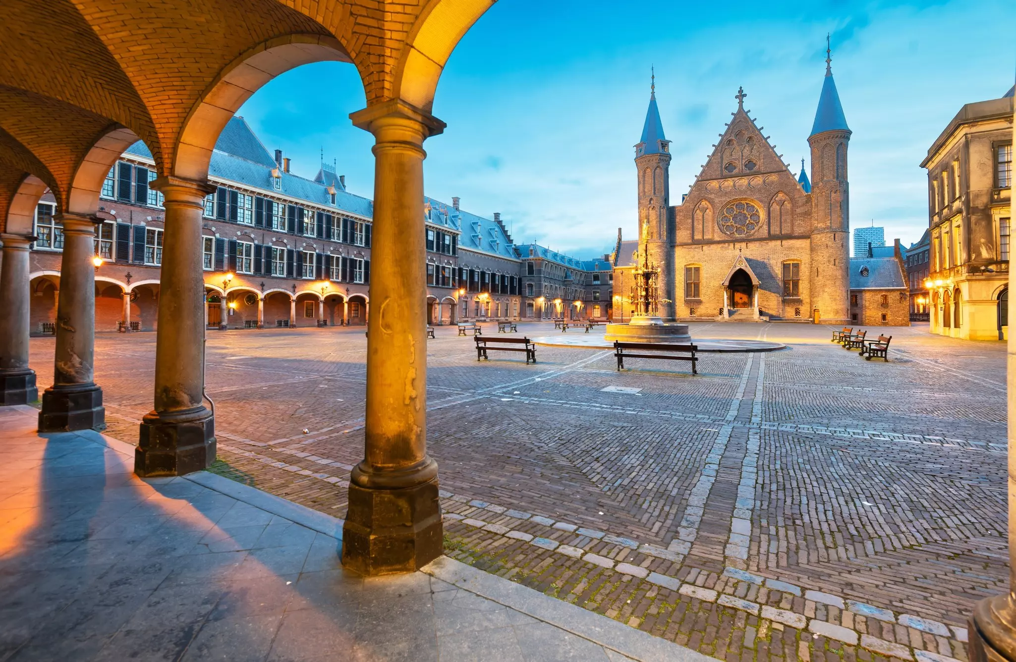 An enclosed space with a church to one side and columns creating a covered walkway on two sides.