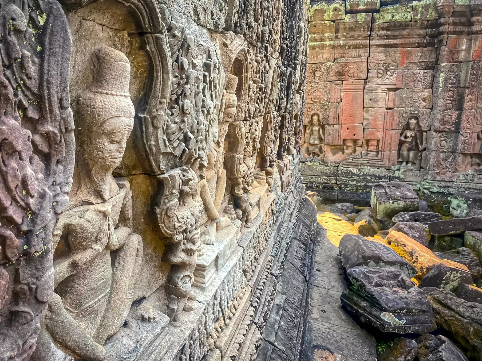 A long side view of relief sculptures on stone at a temple complex in Cambodia.