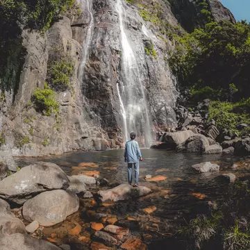 A man standing in front of Bambarakanda Falls, the tallest waterfall in Sri Lanka.