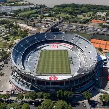 Aerial view of a soccer stadium in Buenos Aires with the city and water around it. 