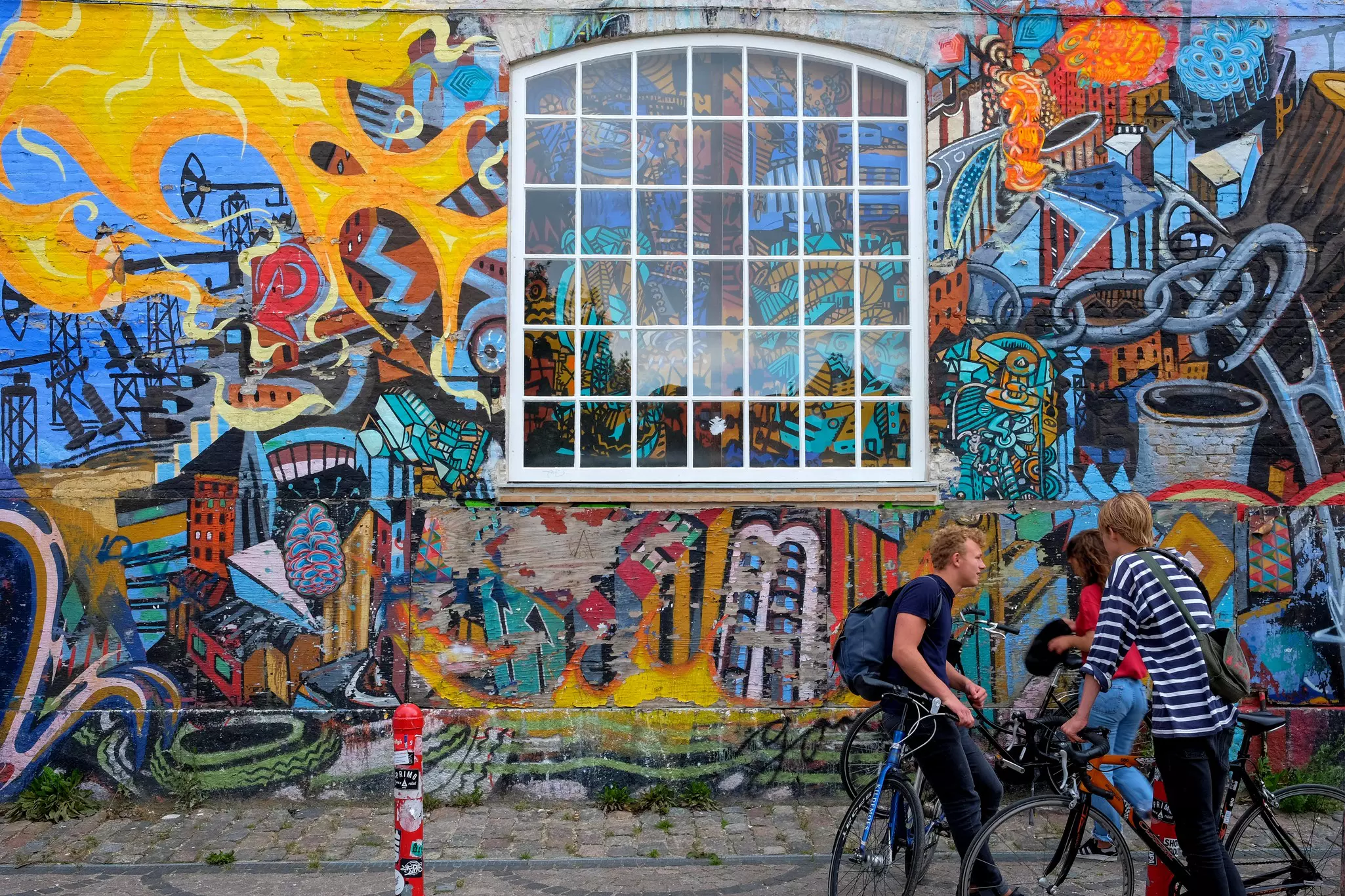 People with bikes in front of walls covered in colorful graffiti.