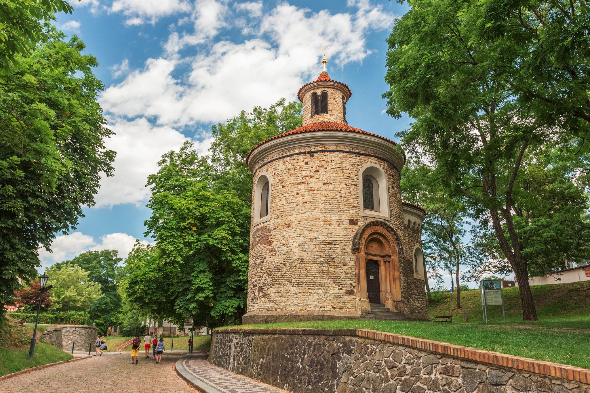 St. Martin rotunda, Vysehrad, Prague, Czech Republic. People walking to the left and blue cloudy sky above. 