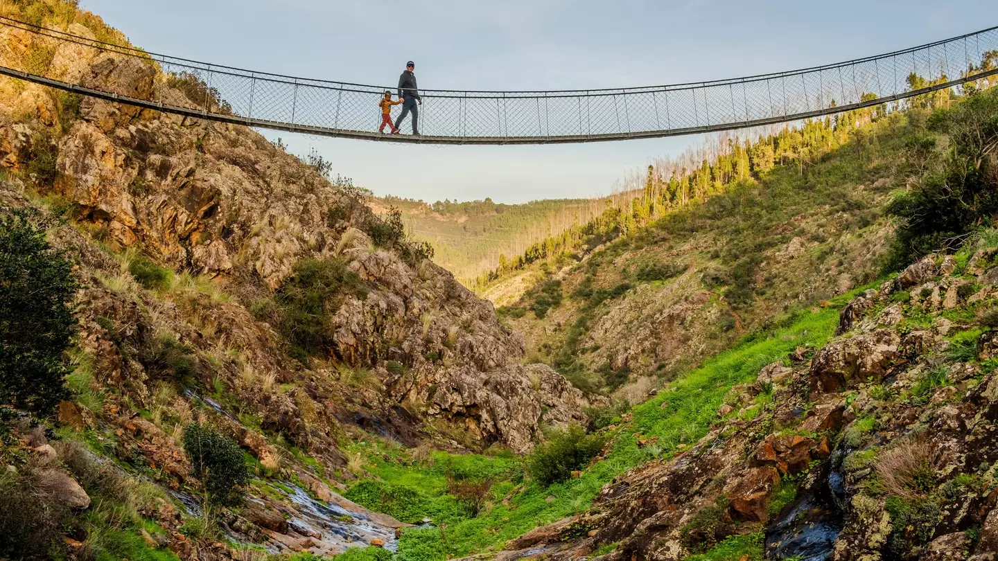 A father and son walk across a hanging bridge in the village of Alferce in Portugal.