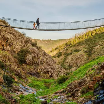 A father and son walk across a hanging bridge in the village of Alferce in Portugal.