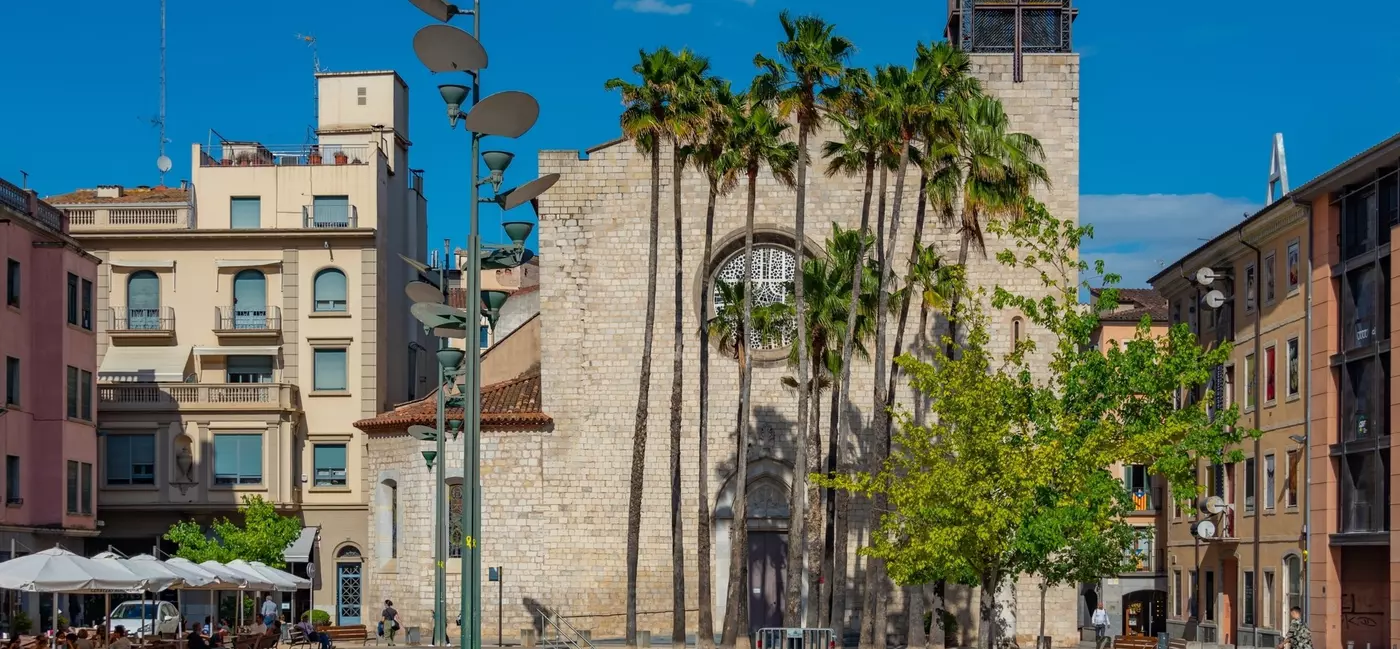A church located in a public square. Restaurants with outdoor tables are on either side of the church. 