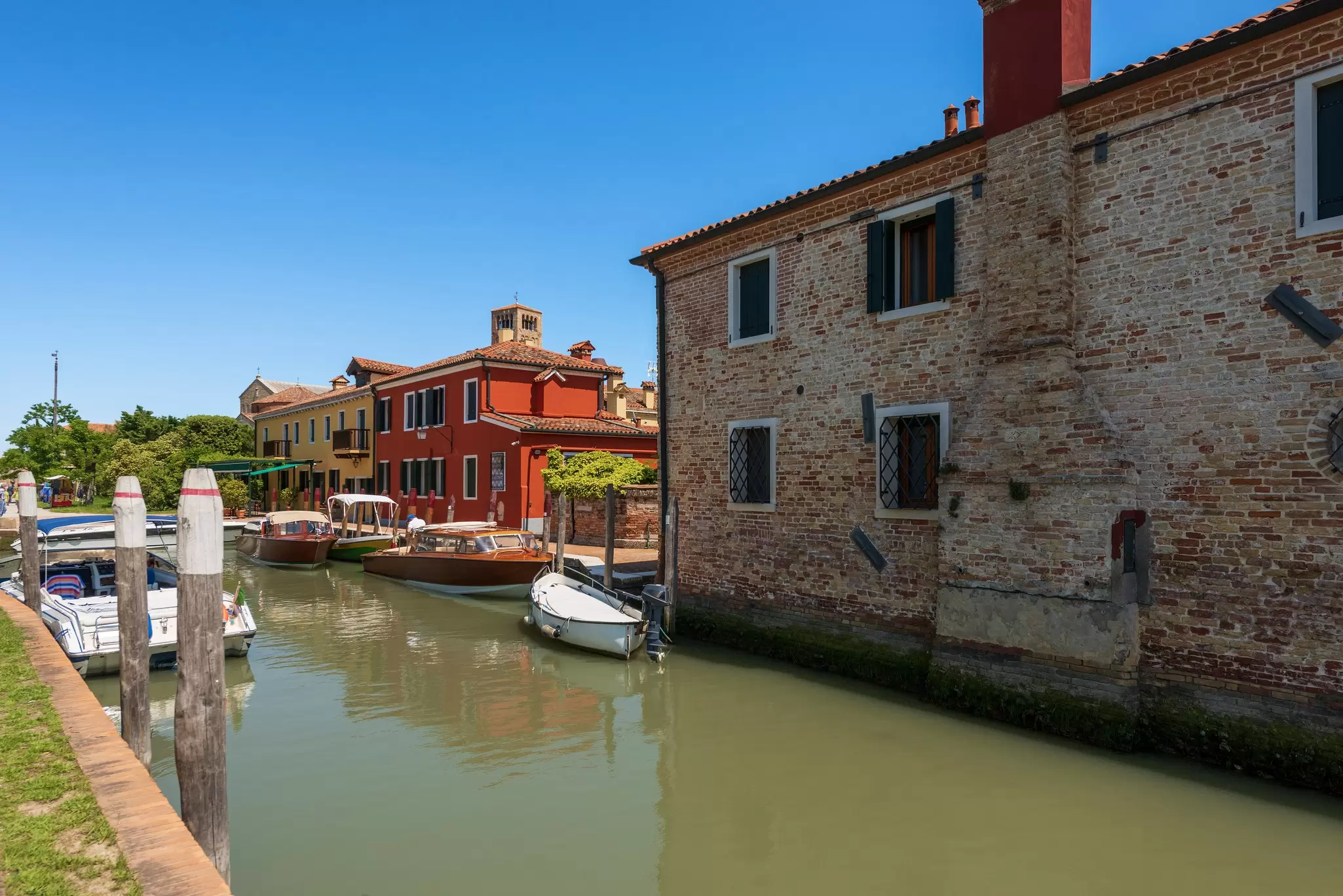 Motor boats and traditional water taxis in the small port of the island of Torcello in the Venetian lagoon in Italy.