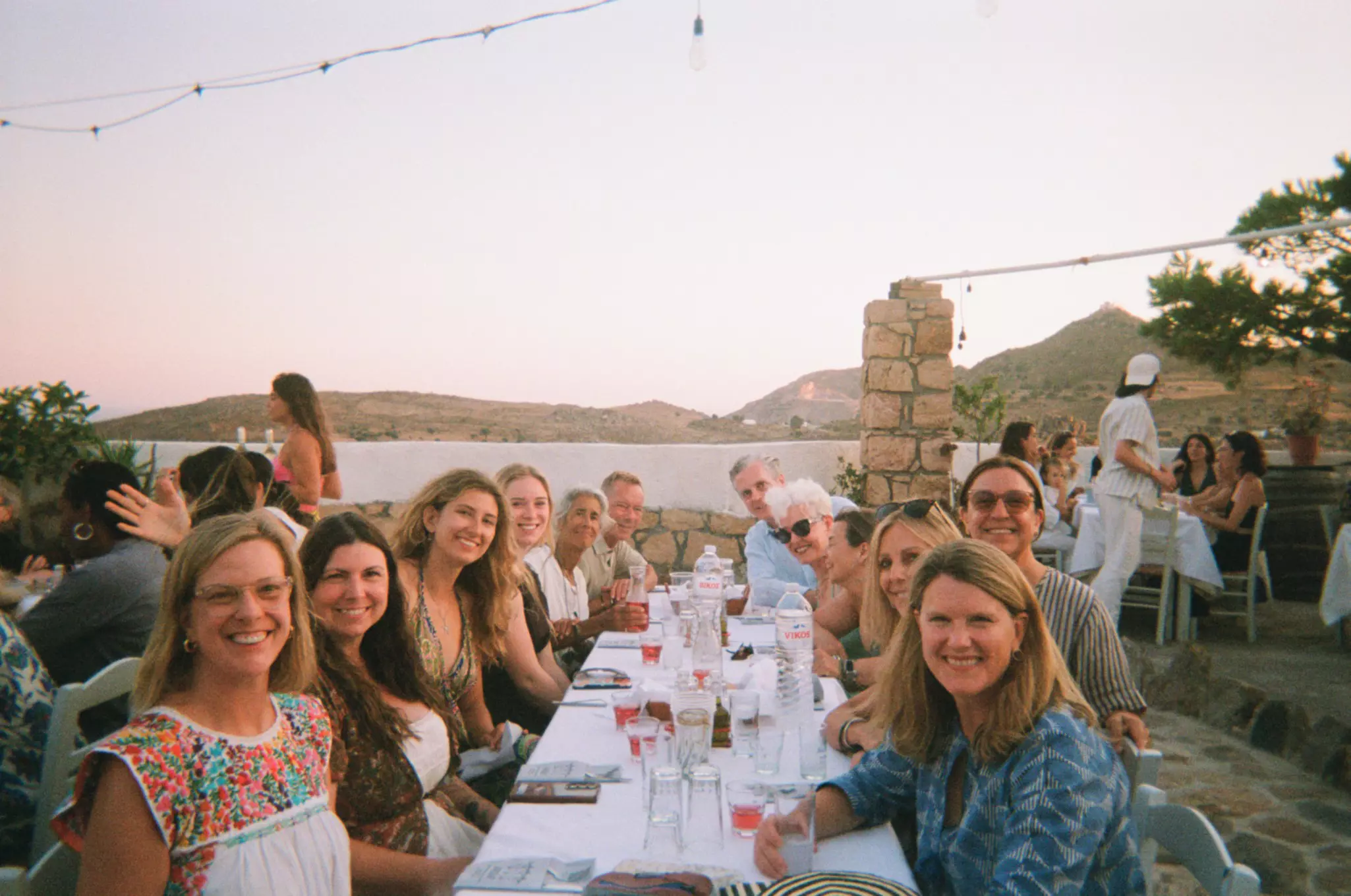 A group of people smile around a table in Greece